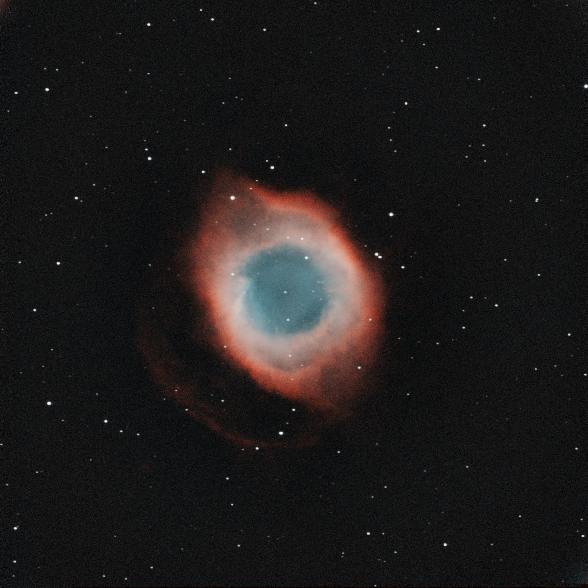 A roughly oval shape that looks remarkably like a human eye, with a translucent baby blue center, surrounded by hazy white, outlined by wispy orange gas.  In the backdrop is a starfield speckled with white specks of light.